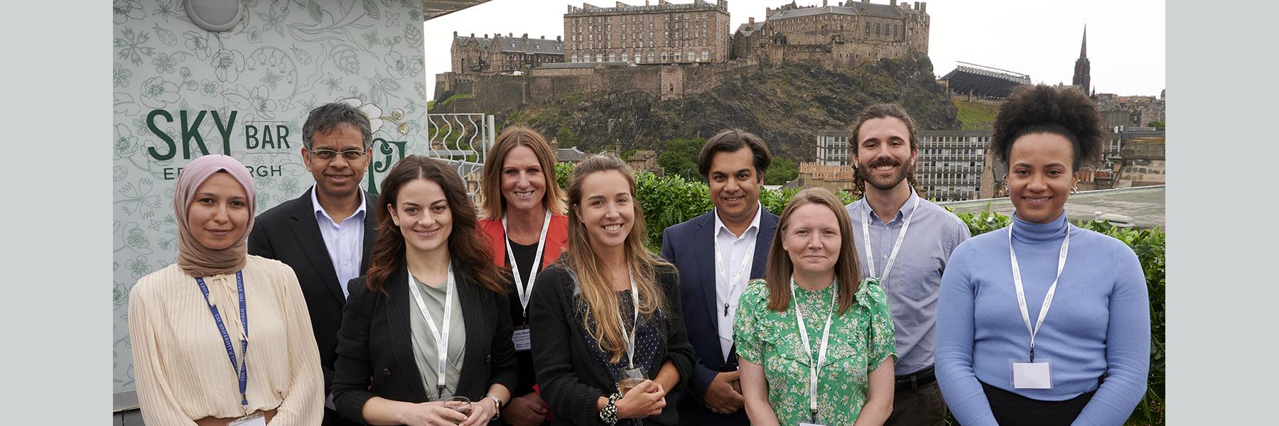 A group photo of 9 members of the MND-SMART core team, taken outside, with Edinburgh Castle in the background